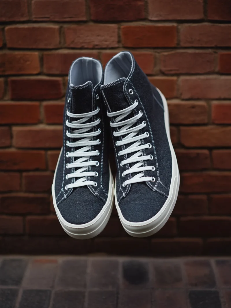 Anthrazitfarbene Canvas-Hightops an einer Backsteinwand